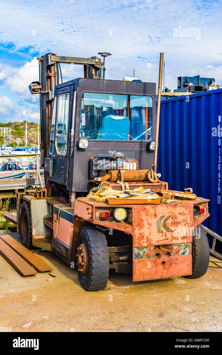 Marstrand, Svezia - 8 Settembre 2016: ambientale documentario del vecchio muletto parcheggiato a fianco di un contenitore in un marina. Foto Stock