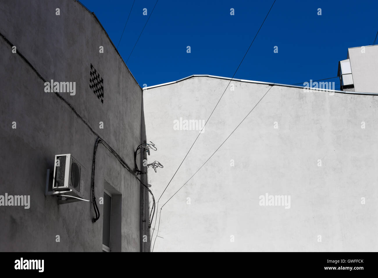 Vecchio stucco grigio della parete edilizia sullo sfondo del cielo blu, città abstract Foto Stock