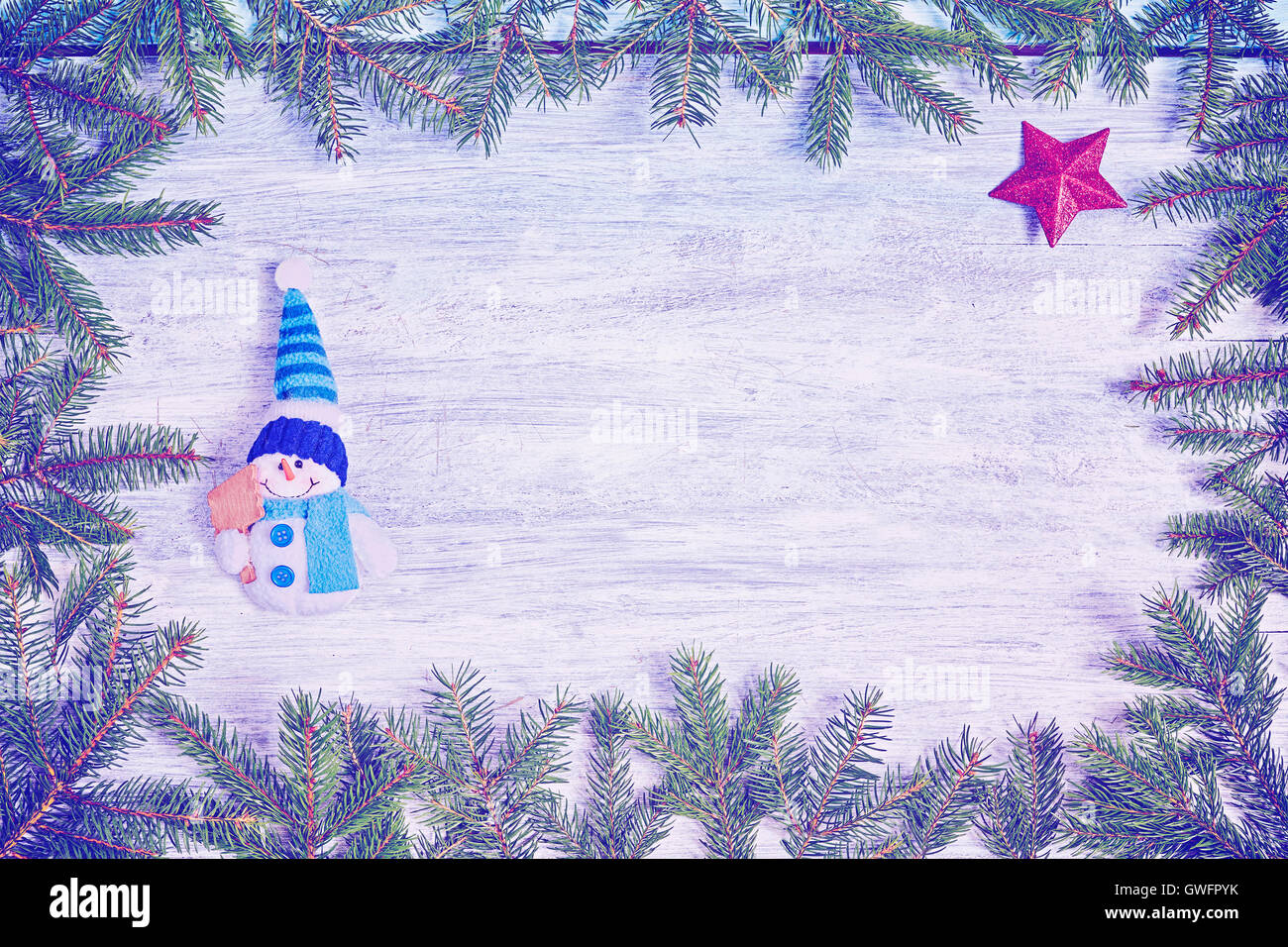 Vintage tonalità dello sfondo di Natale, Abete rami frame con un pupazzo di neve e la stella rossa su una tavola in legno rustico, vista dall'alto con co Foto Stock