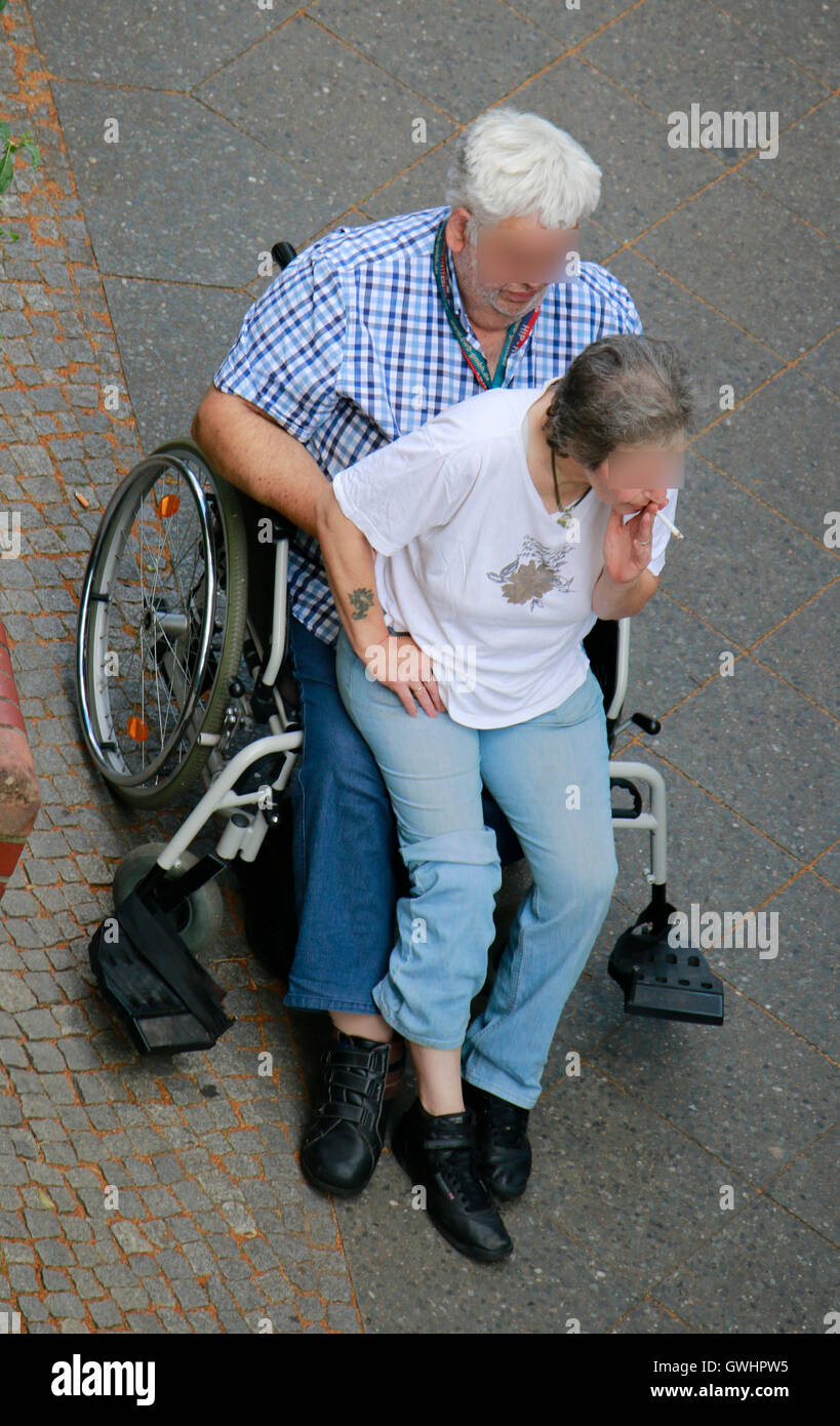 Mann und Frau im rauchend Rollstuhl, Berlin-Prenzlauer Berg. Foto Stock