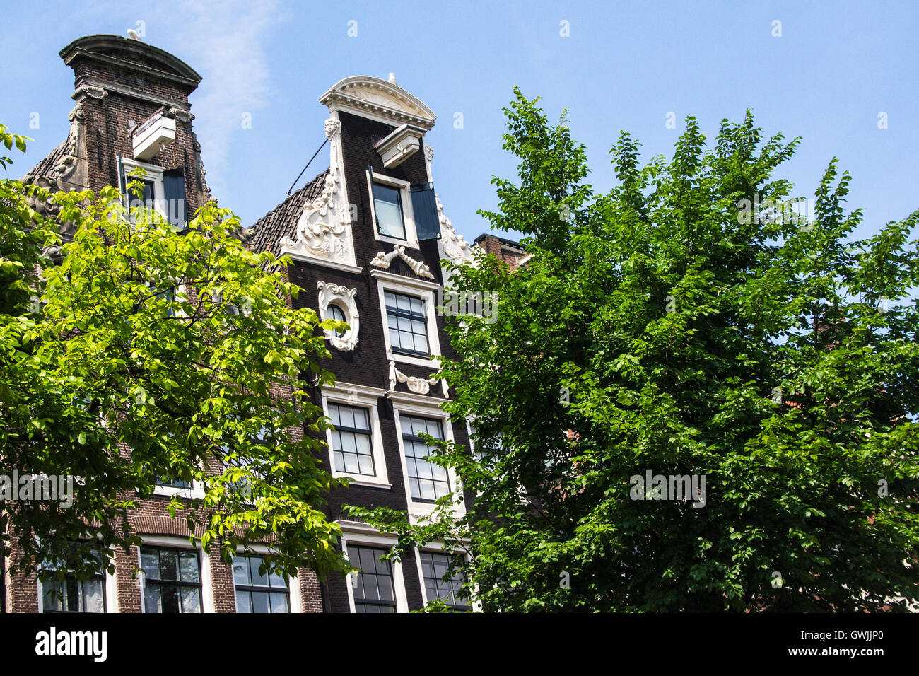 Facciata di case su un canale ad Amsterdam contro un cielo blu Foto Stock
