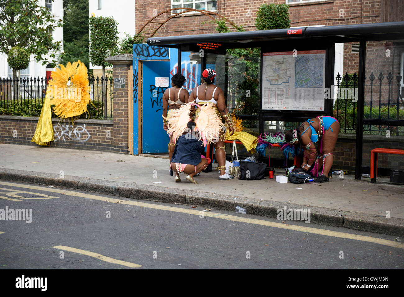 Festaioli sono dressing fino al bus stop di mattina presto, la preparazione per il carnevale di Notting Hill celebrazioni Foto Stock