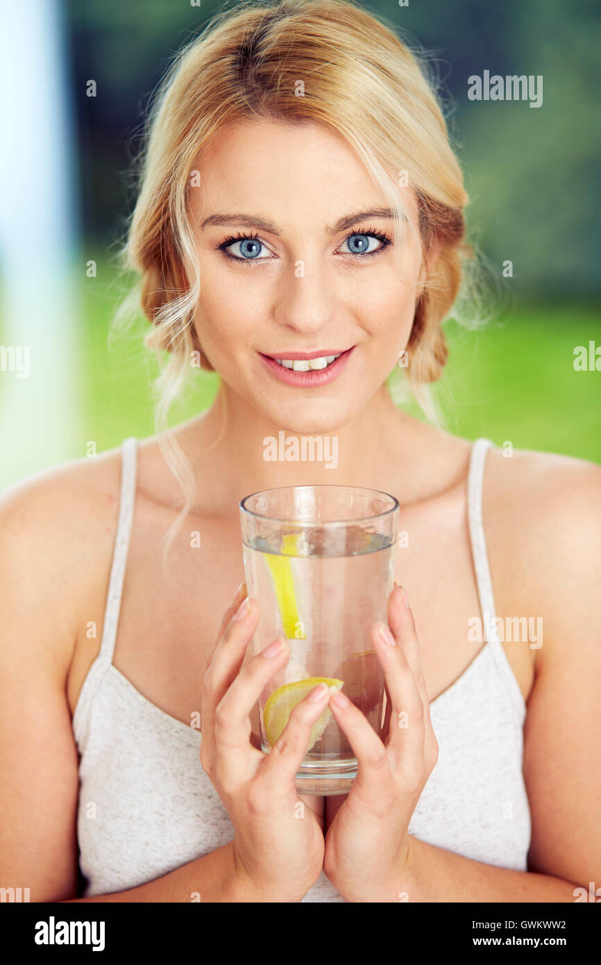 Ragazza di bere un bicchiere di acqua ghiacciata al limone Foto Stock