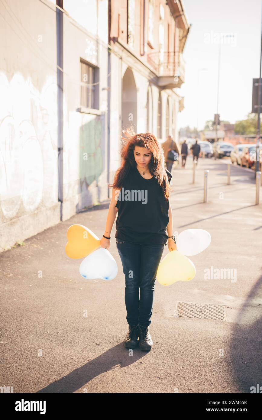 Giovani marrone rossiccio capelli donna caucasica giocare in strada con il palloncino a forma di cuore - Gioventù, Infanzia, carefreeness co Foto Stock