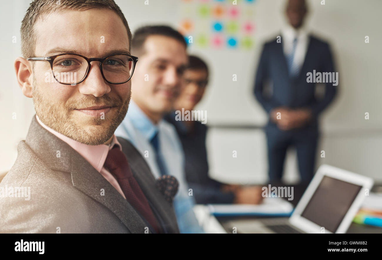 Il gruppo di quattro multi-culturale di alti dirigenti in un incontro presso il loro ufficio nella parte anteriore del computer portatile e di una lavagna bianca Foto Stock
