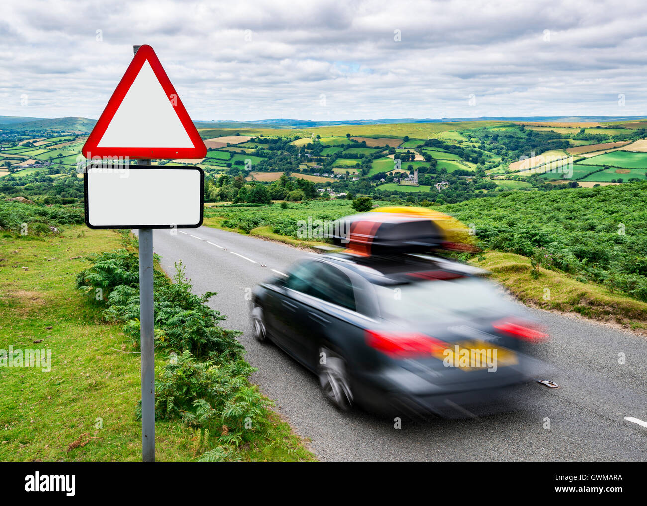 Un Holiday Maker's car scende giù per una ripida collina nella campagna, passando un cartello con una copia dello spazio. Foto Stock