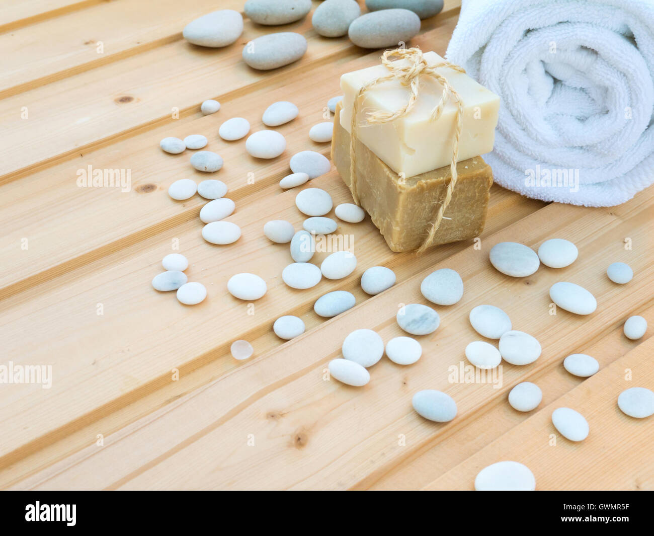 Laminato bianco asciugamano, saponette legati con corda di iuta e pietre su tavole di legno Foto Stock