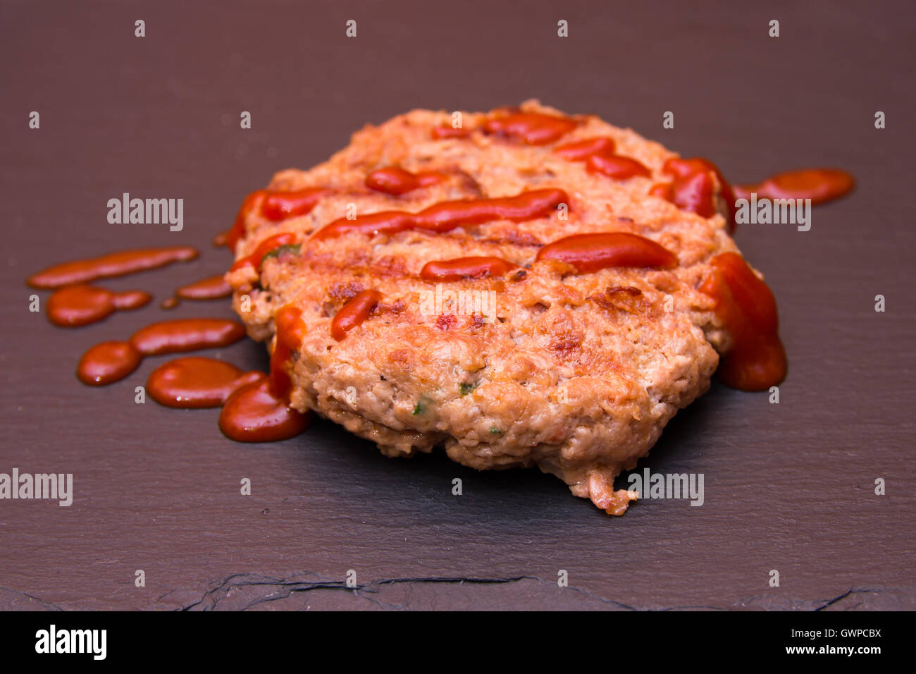 Polpetta con ketchup su un pavimento di ardesia Foto Stock