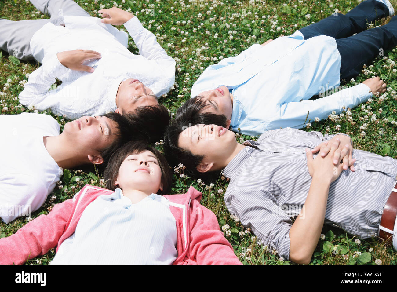 Un gruppo di giovani amici giapponesi che posa in erba Foto Stock