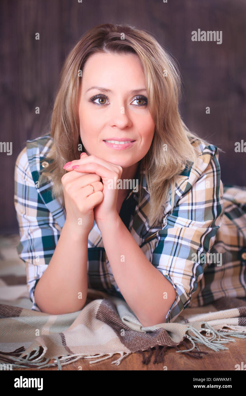 Ritratto di una giovane donna attraente giacente su un plaid Coperte, close-up verticale, riprese in studio Foto Stock