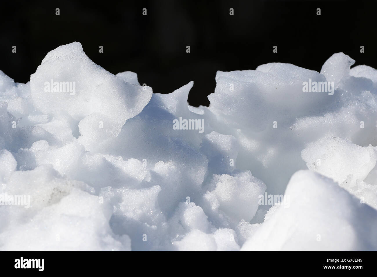 Luci e ombre su un pulito bianco della neve pila contro uno sfondo scuro Foto Stock