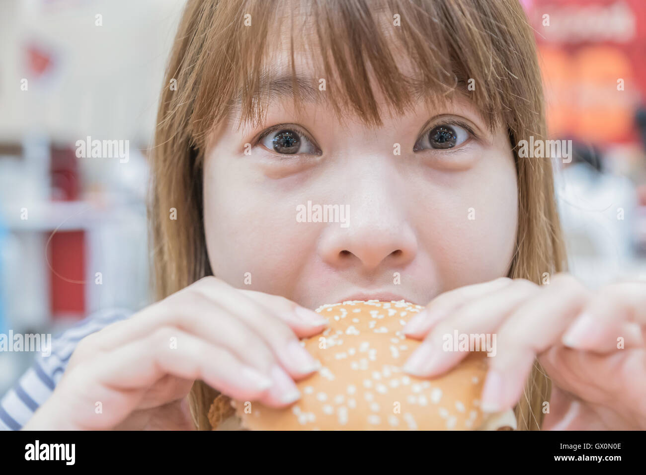 La bellezza della donna in cafe mangiare hamburger Foto Stock