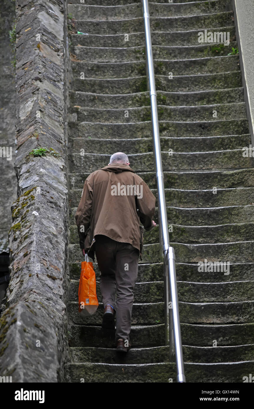 Un uomo cammina fino scalini molto ripidi. Foto Stock