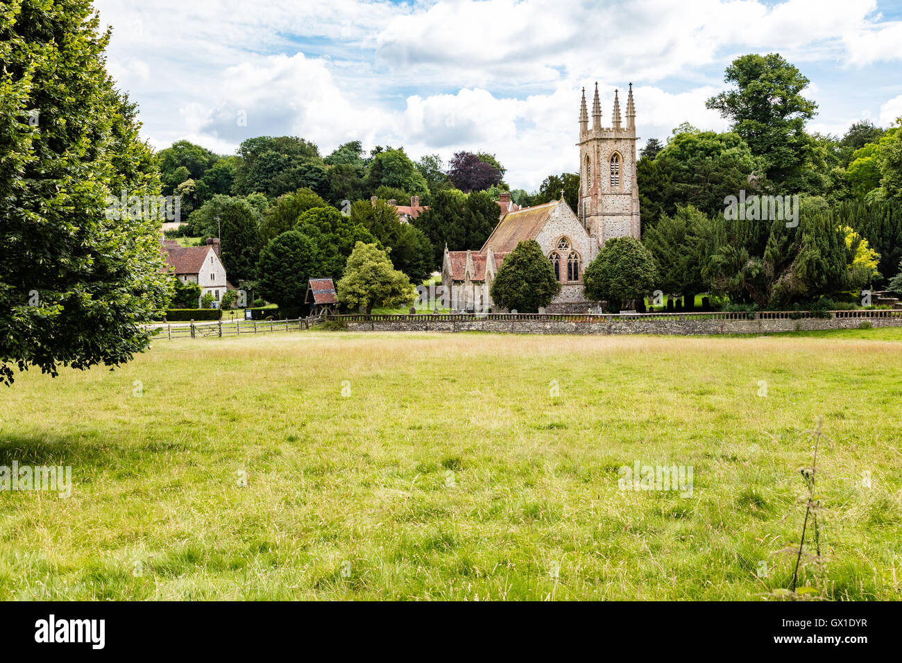 La Chiesa di San Nicola accoccolato tra gli alberi sulla casa Chawton parkland, Hampshire, Regno Unito Foto Stock