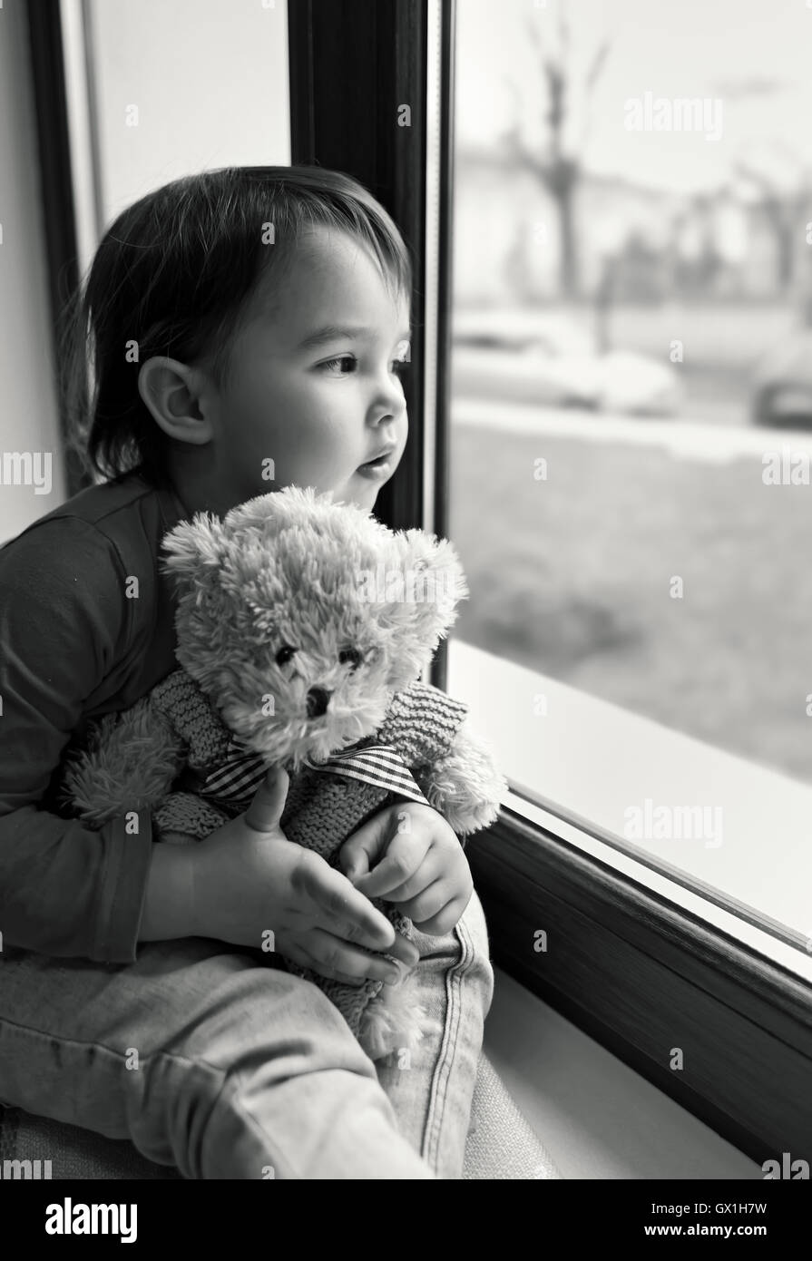 Bambina guardando fuori dalla finestra a casa Foto Stock