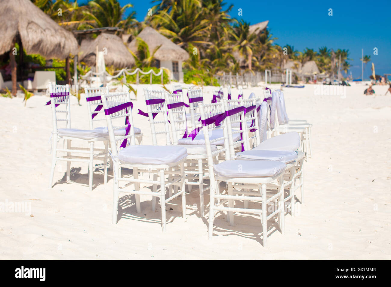 Nozze Bianche sedie decorate con archetti viola sulla spiaggia sabbiosa Foto Stock