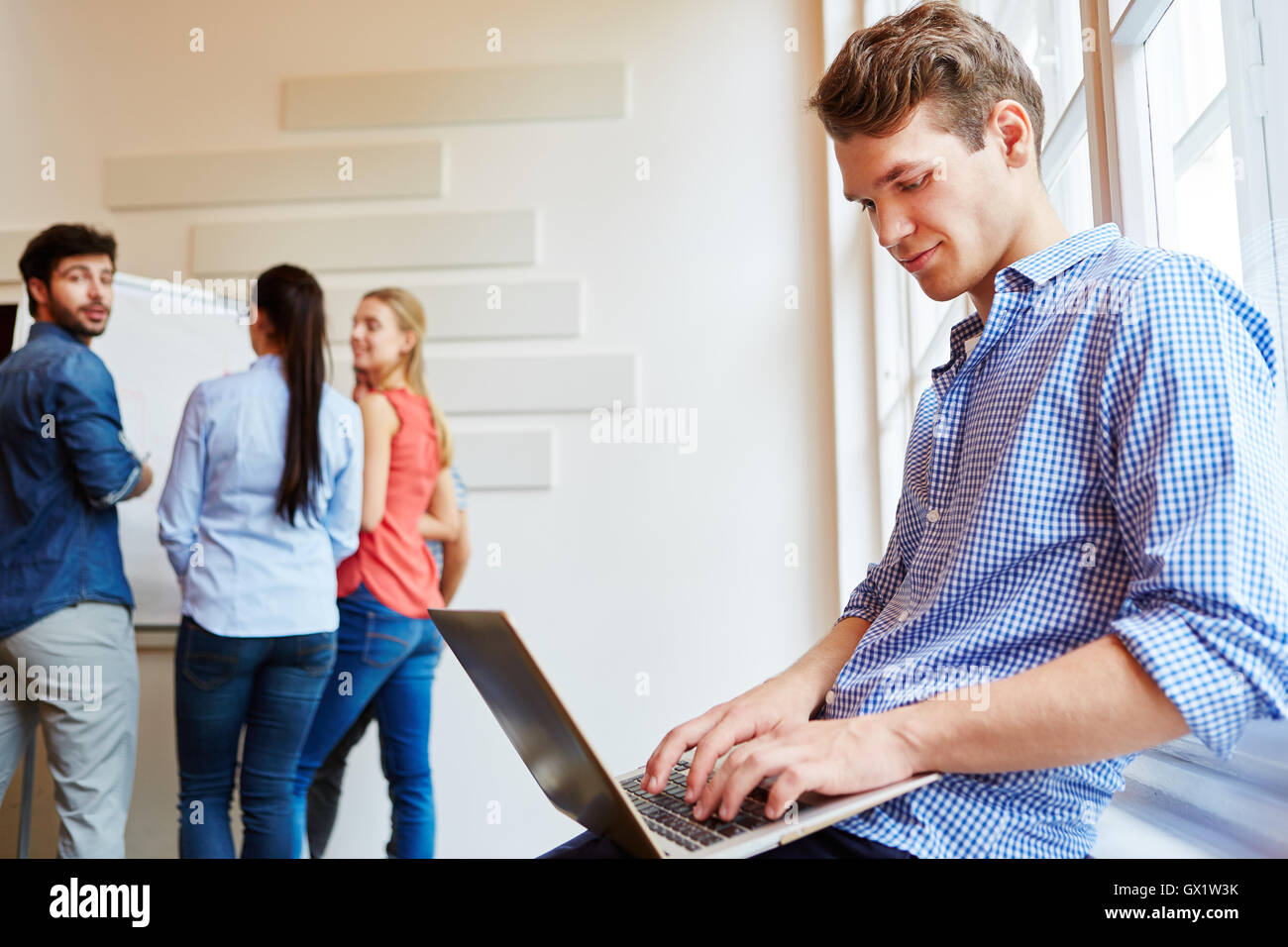 Giovane imprenditore lavora con il computer portatile nella sua azienda start-up Foto Stock