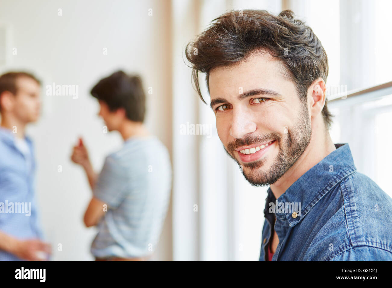 Giovane uomo come studente sorridente felicemente nella sua azienda start-up Foto Stock