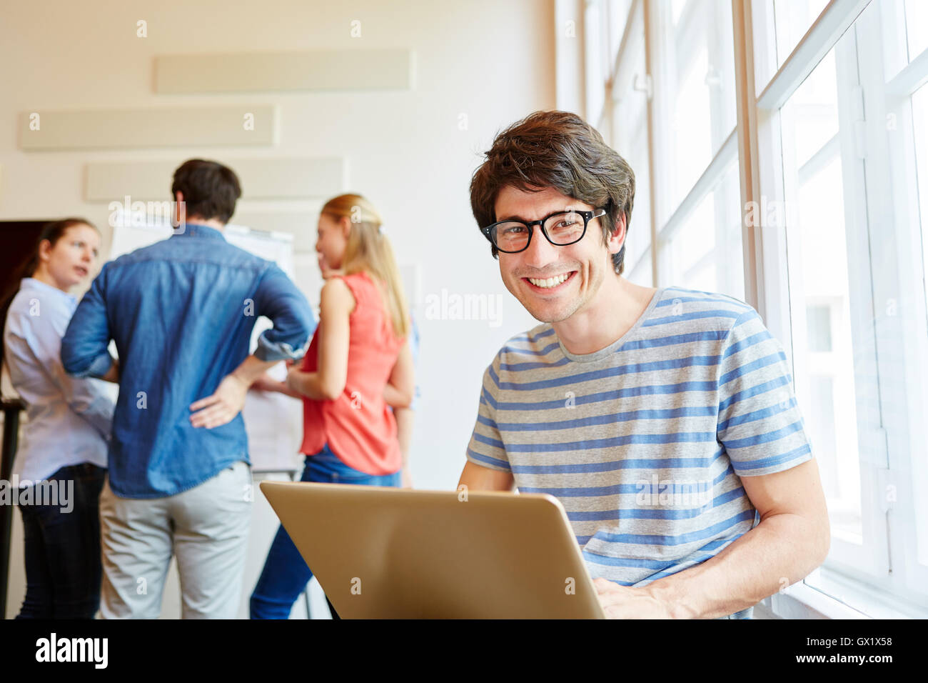 Studente di successo con il computer portatile sorridente con gioia in una start-up Foto Stock