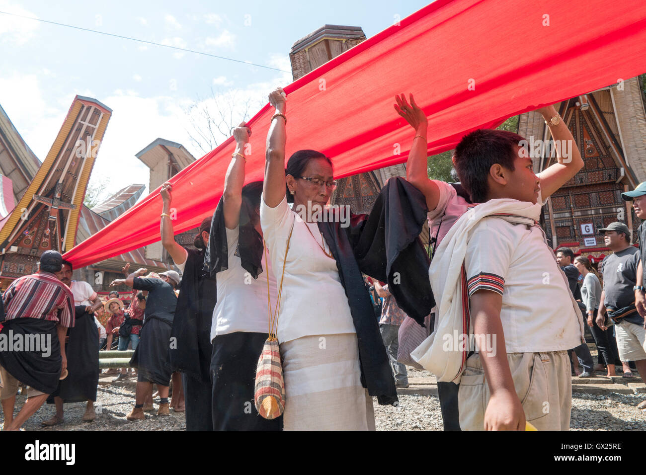 Familiari e parenti sparsi un lungo panno rosso o Kain Merah parade, con la bara in più arretrata durante l'assolo Rambu Foto Stock
