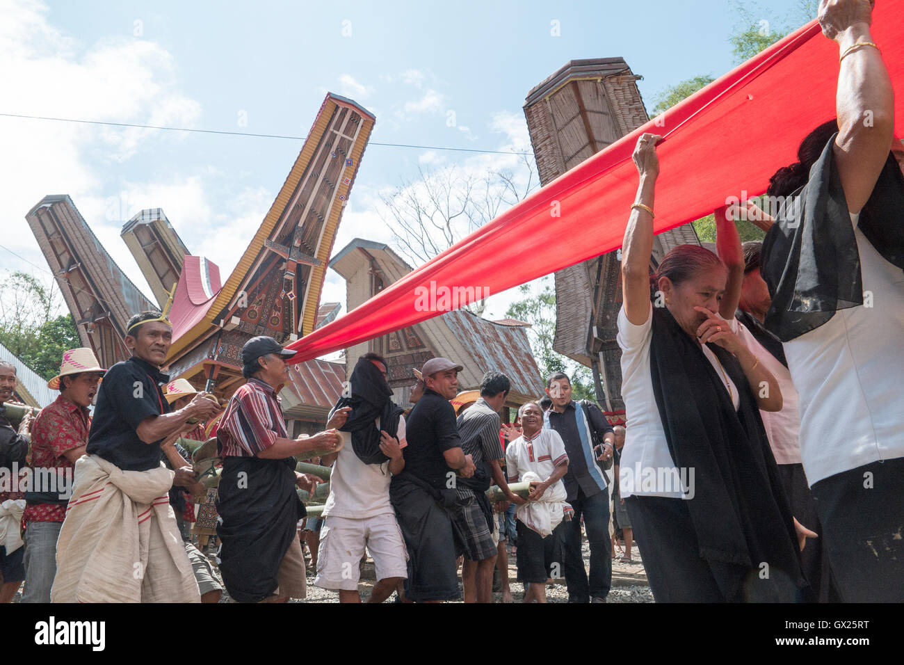 Familiari e parenti sparsi un lungo panno rosso o Kain Merah parade, con la bara in più arretrata durante l'assolo Rambu Foto Stock