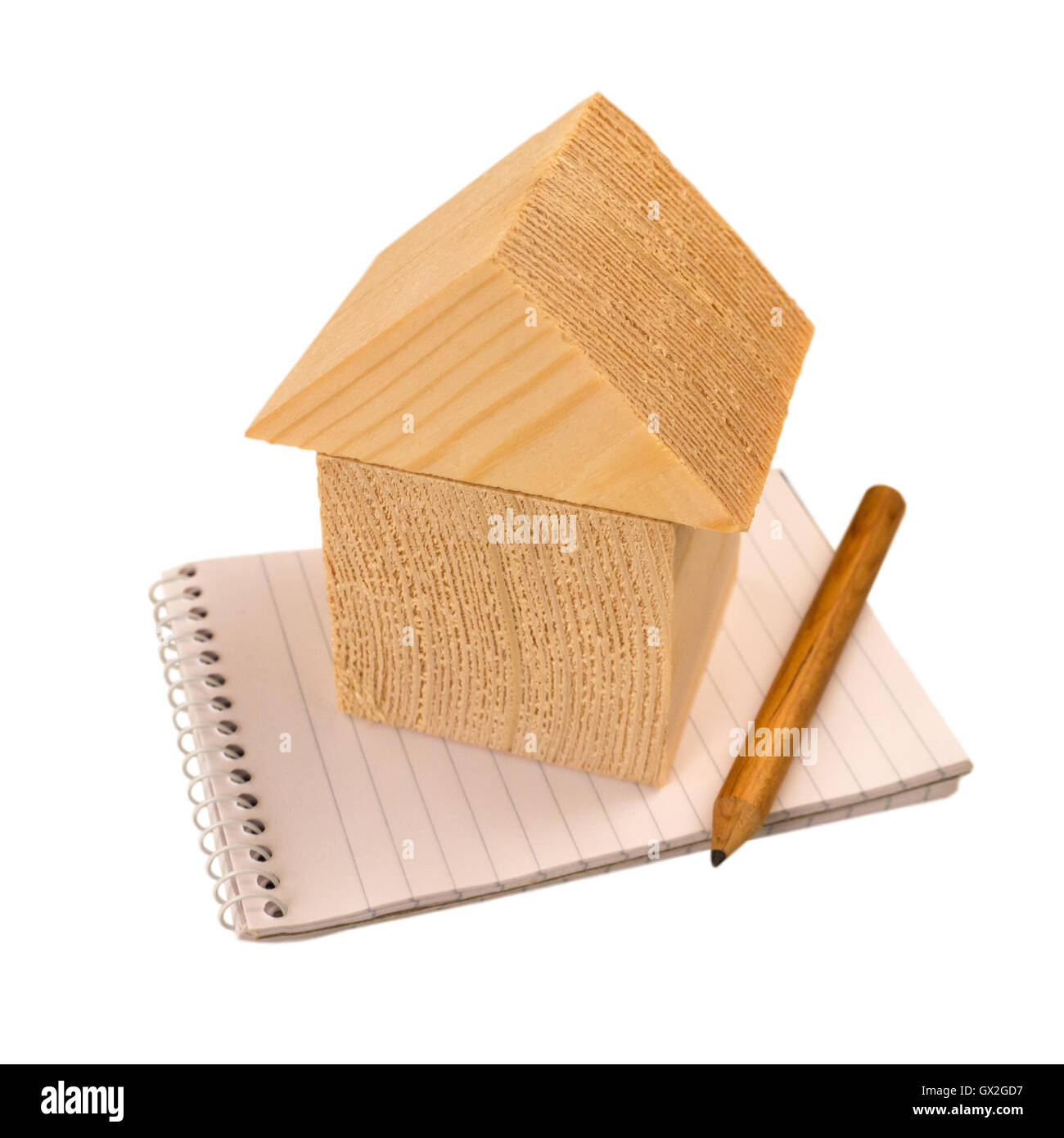 Casa dei blocchi di legno in piedi su un notebook con una matita isolato su bianco Foto Stock