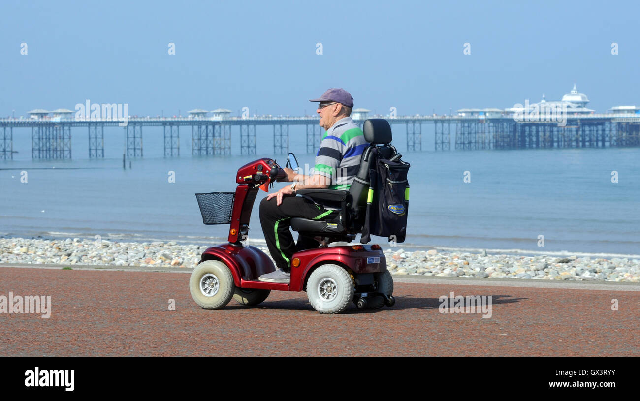 L UOMO SULLA MOBILITÀ SCOOTER sul lungomare a Llandudno North Wales re cura di invalidità pensionabile anziani pensionati mare REGNO UNITO Foto Stock