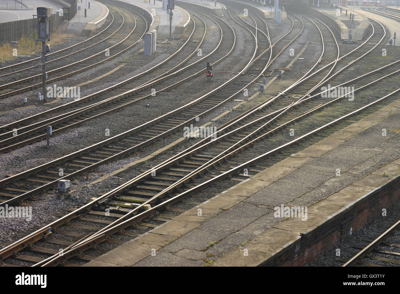 Sole di mattina glinting su binari piattaforme linee dello scafo della stazione ferroviaria di Inghilterra Foto Stock