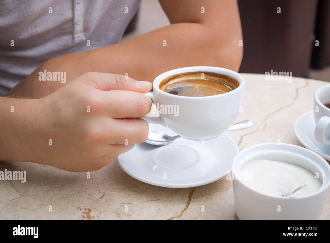Uomo al tavolo di marmo contiene una tazza di caffè americano nella sua  mano Foto stock - Alamy