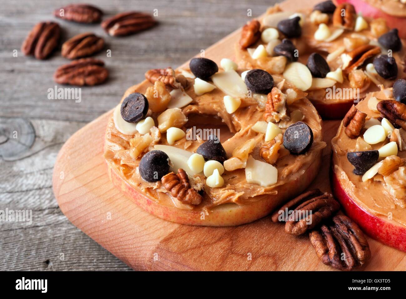 Autunno Apple arrotonda con burro di arachidi, scaglie di cioccolato e i dadi su una paletta di legno board Foto Stock