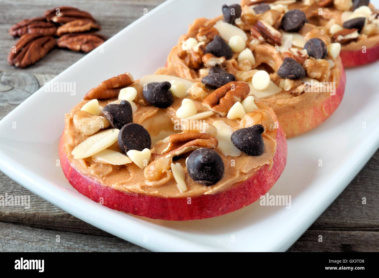 Autunno Apple arrotonda con burro di arachidi, scaglie di cioccolato e noci, su bianco piatto Foto Stock