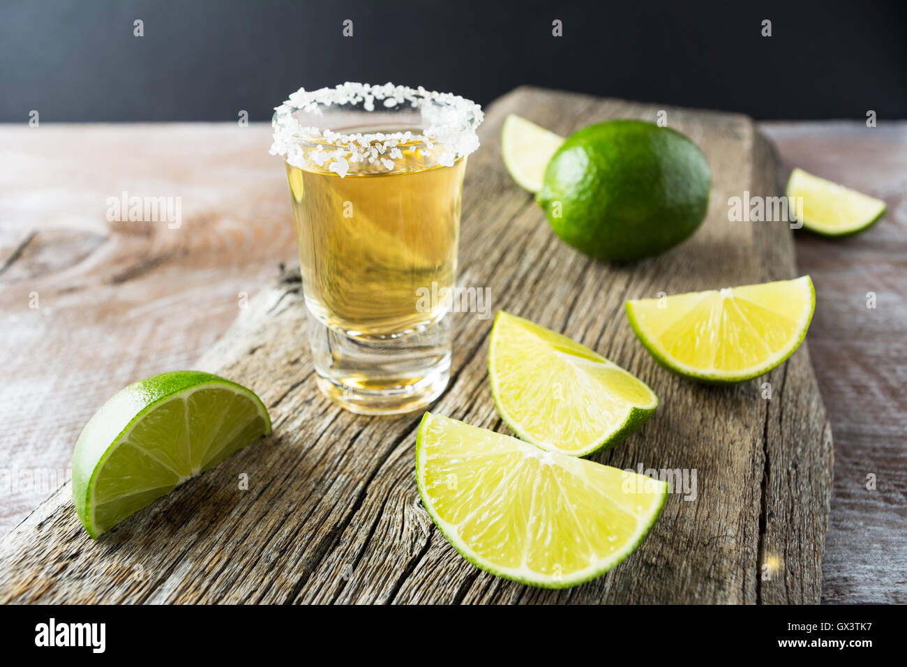 Tequila shot con calce su legno rustico sfondo. Forte bere alcool. Oro tequila messicana shot. Foto Stock