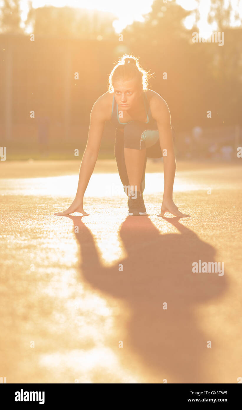 Giovane ragazza adolescente sprinter posizione start all'aperto giorno di sole lens flare Foto Stock