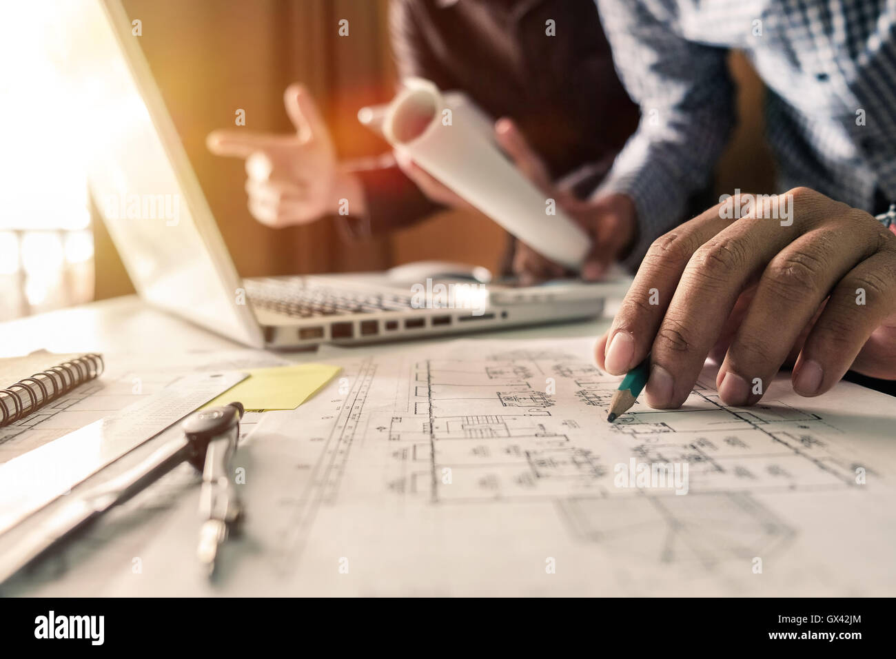 Due colleghi discutono dei dati di lavoro, tablet portatile con sul progetto architettonico al sito in costruzione a scrivania in ufficio Foto Stock