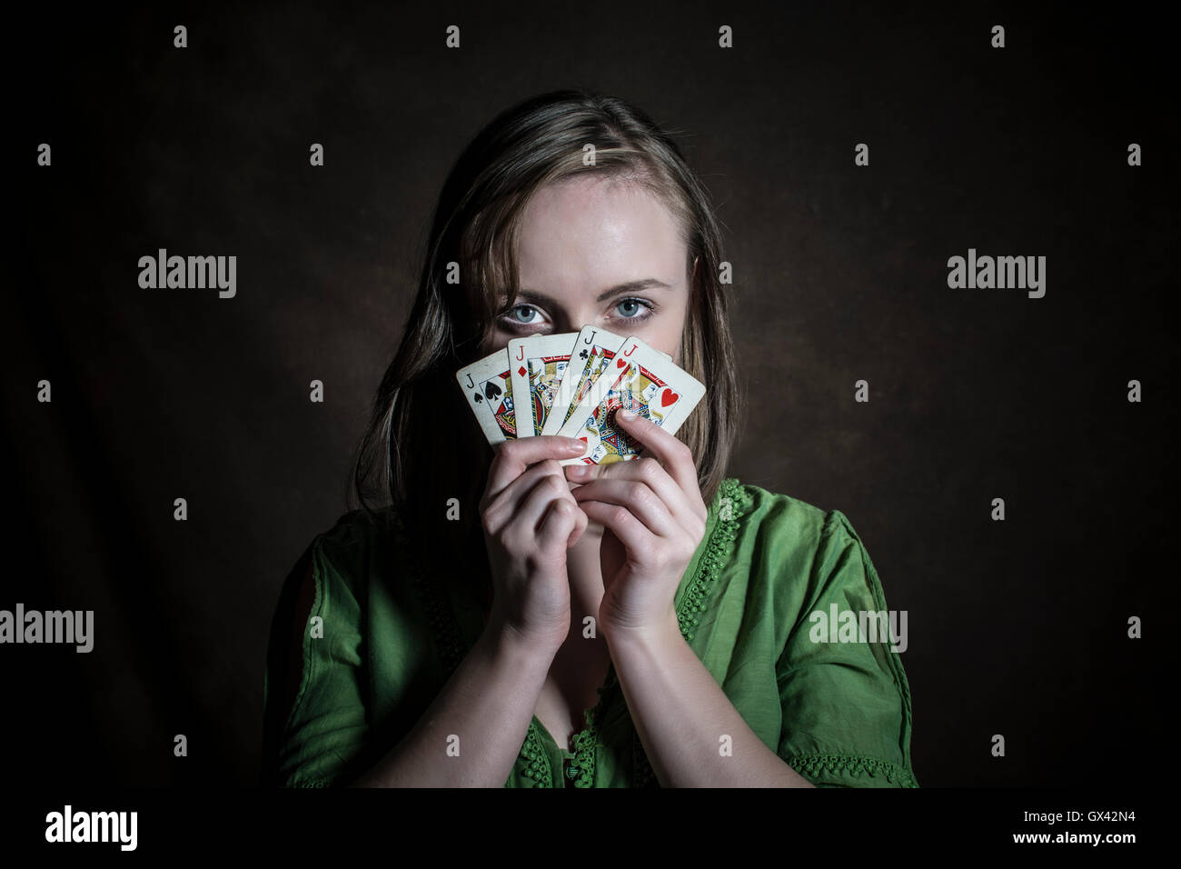 La donna nasconde il viso con le carte da gioco Foto Stock
