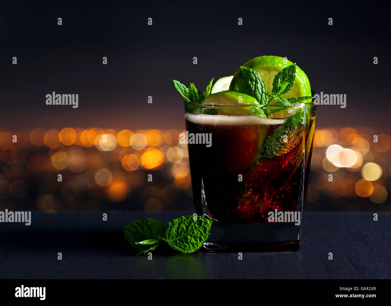 Cola con calce , ghiaccio e menta piperita sullo sfondo della città di notte Foto Stock