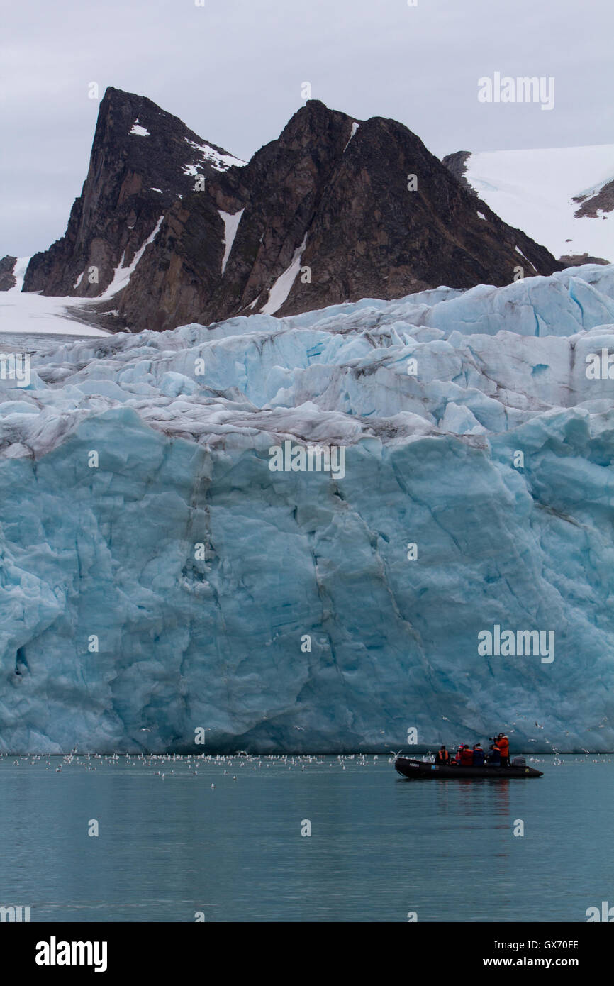 Zodiac barca piena di turisti nella parte anteriore del ghiacciaio in Svalbard, Norvegia Foto Stock