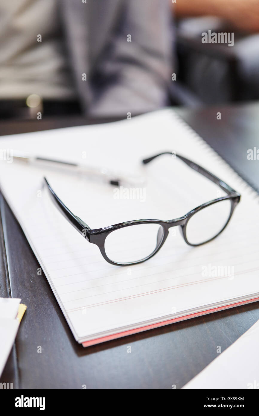 Occhiali su un blocco note in un ufficio durante la pausa di lavoro Foto Stock