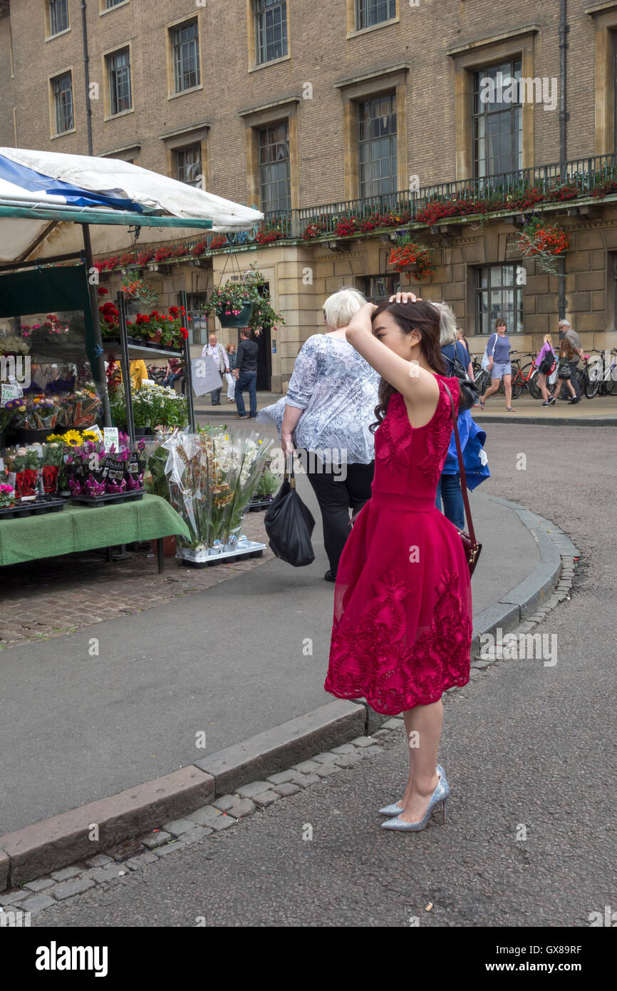 Giovane donna orientale in abito rosso per lo styling dei capelli la Collina di Mercato della città di Cambridge Inghilterra 2016 Foto Stock