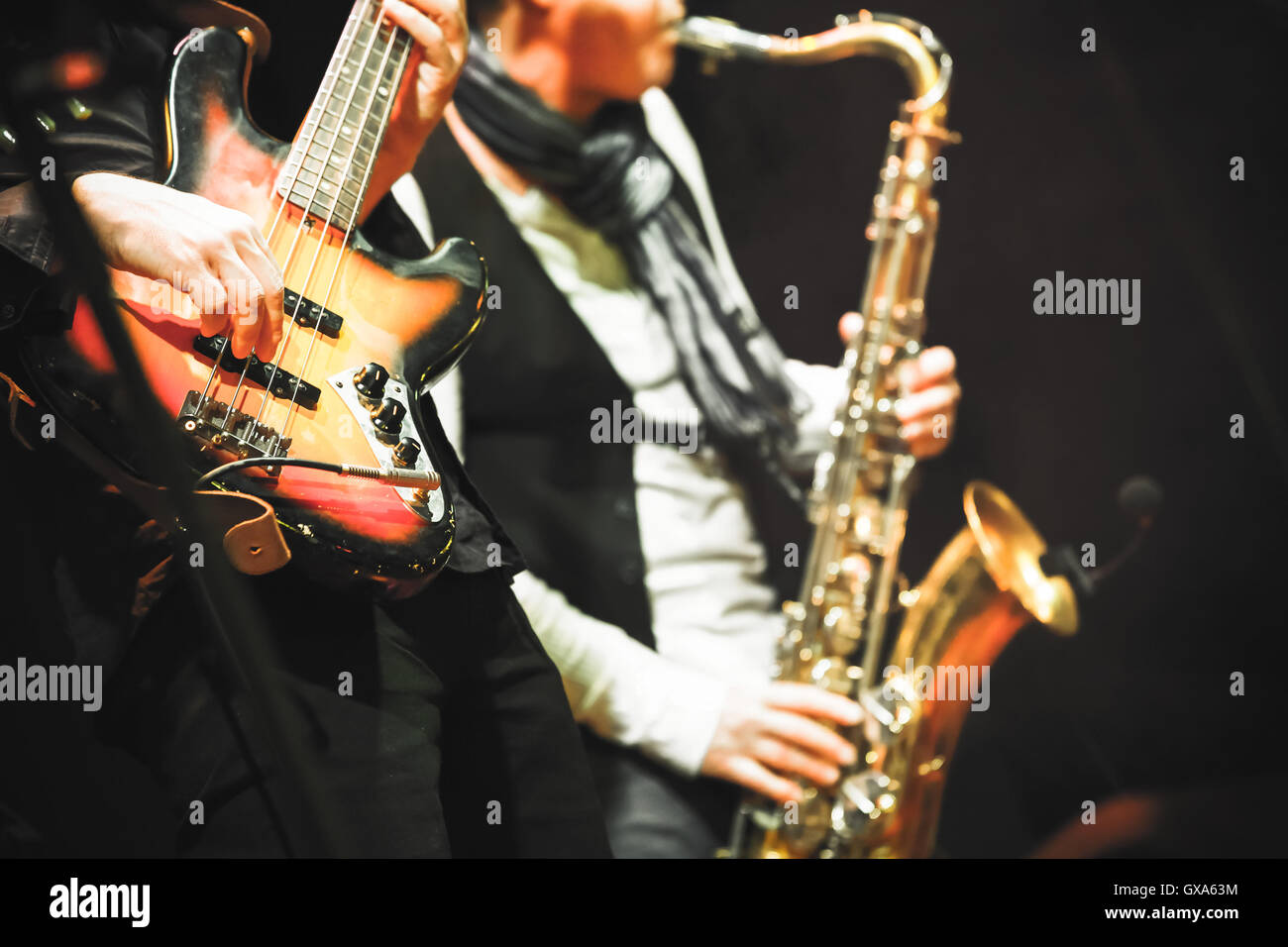 Sottofondo musicale, chitarrista e sassofonista su un palco con illuminazione colorata, foto con messa a fuoco selettiva e retro per Foto Stock