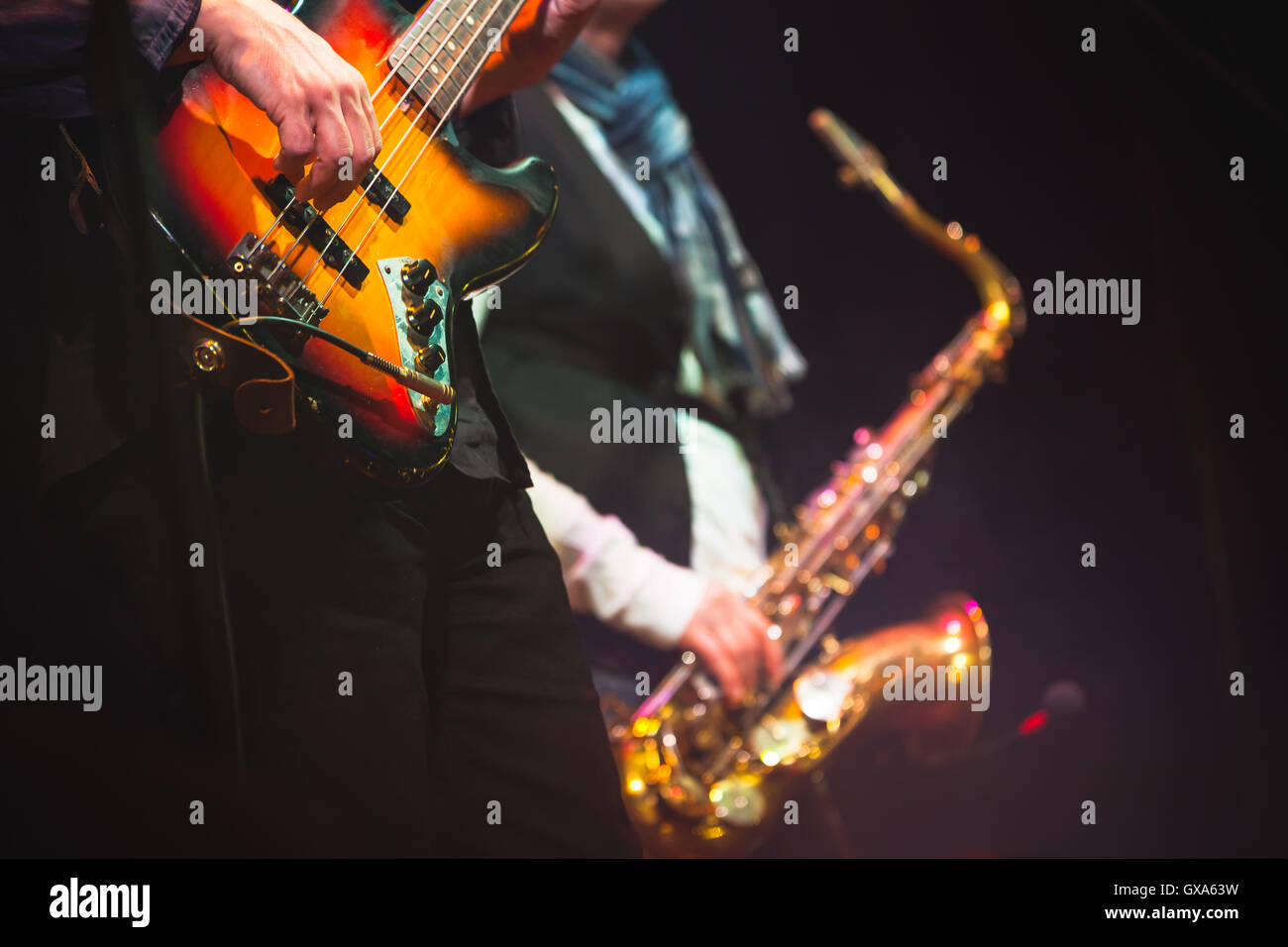 Musica dal vivo di sfondo, chitarrista e sassofonista su un palco con illuminazione colorata, foto con messa a fuoco selettiva e retro Foto Stock