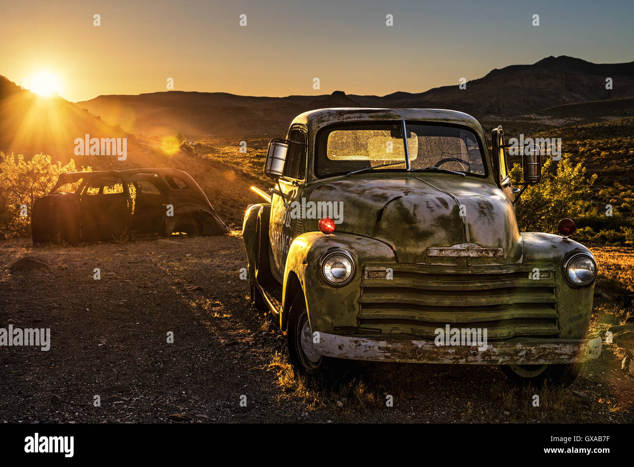 Estate tramonto al di sopra delle auto rottamate nel deserto di Mojave sulla storica Route 66. Foto Stock
