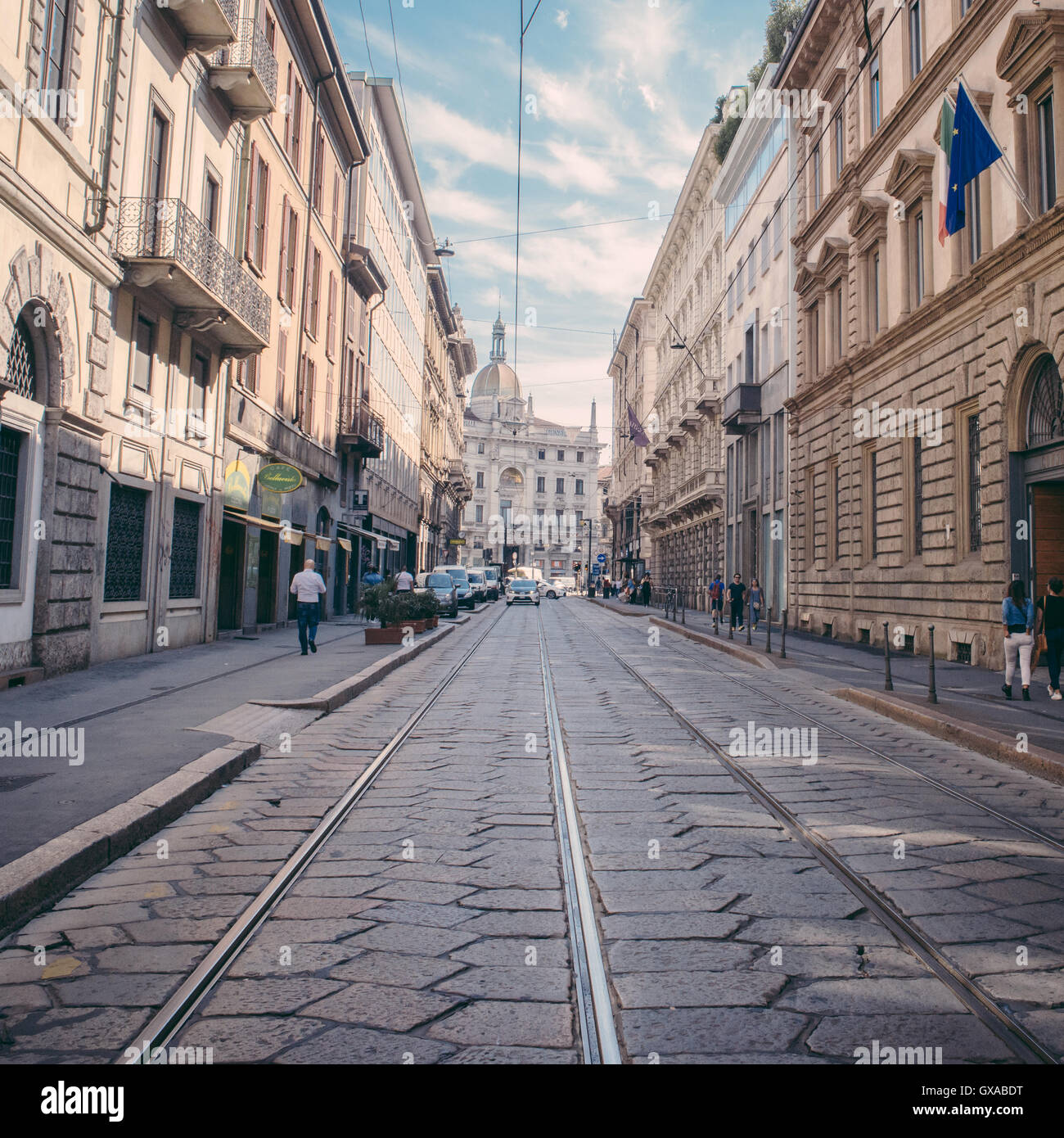 Strada stretta a Milano con i binari del tram e ciottoli Foto Stock