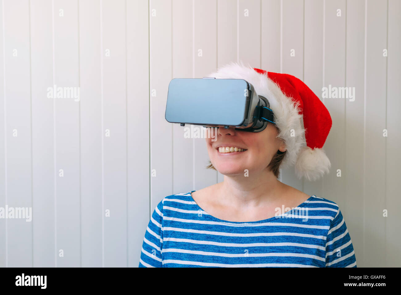 Donna con il Natale di Santa Claus hat e VR occhiali cuffia godendo 360 visualizza il video e la realtà virtuale di contenuti multimediali. Foto Stock
