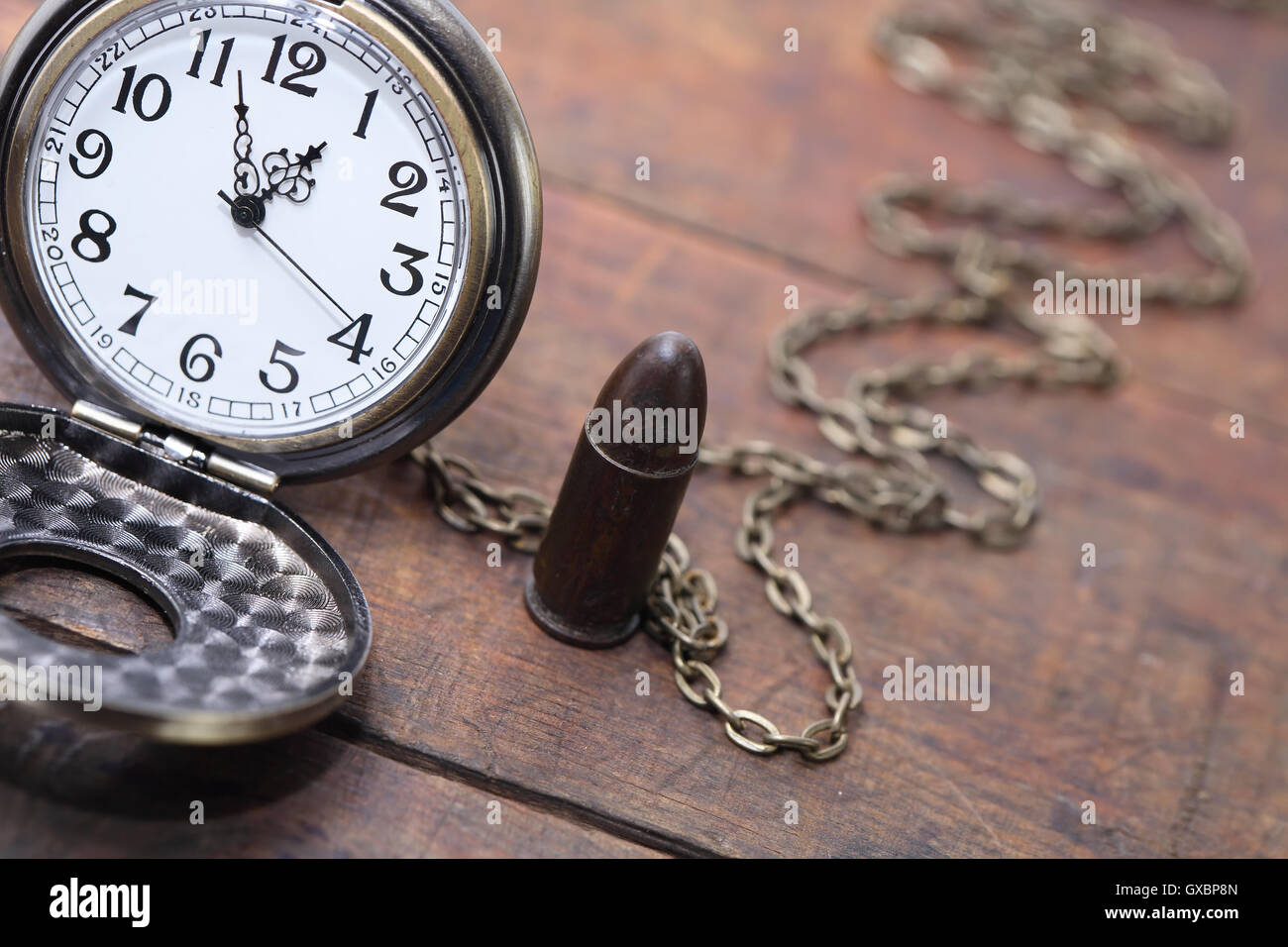 Termine ultimo concetto. Cartuccia per pistola vicino vintage orologio da tasca su sfondo di legno Foto Stock