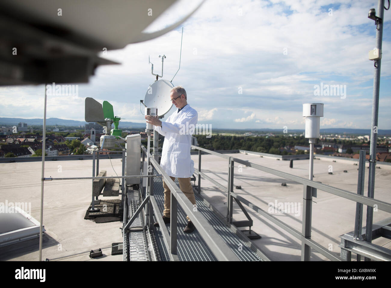 Voce maschile meteorologo aggiornamento attrezzature meteorologiche misurazioni sul tetto della stazione meteo Foto Stock