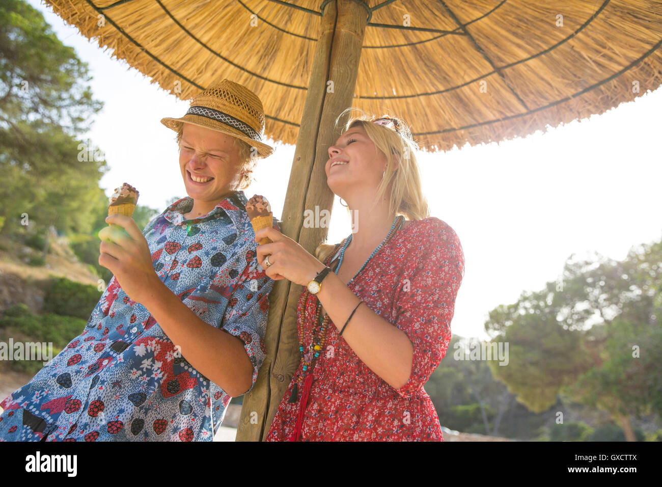 Giovane sotto ombrellone holding coni gelato sorridente, Maiorca, SPAGNA Foto Stock