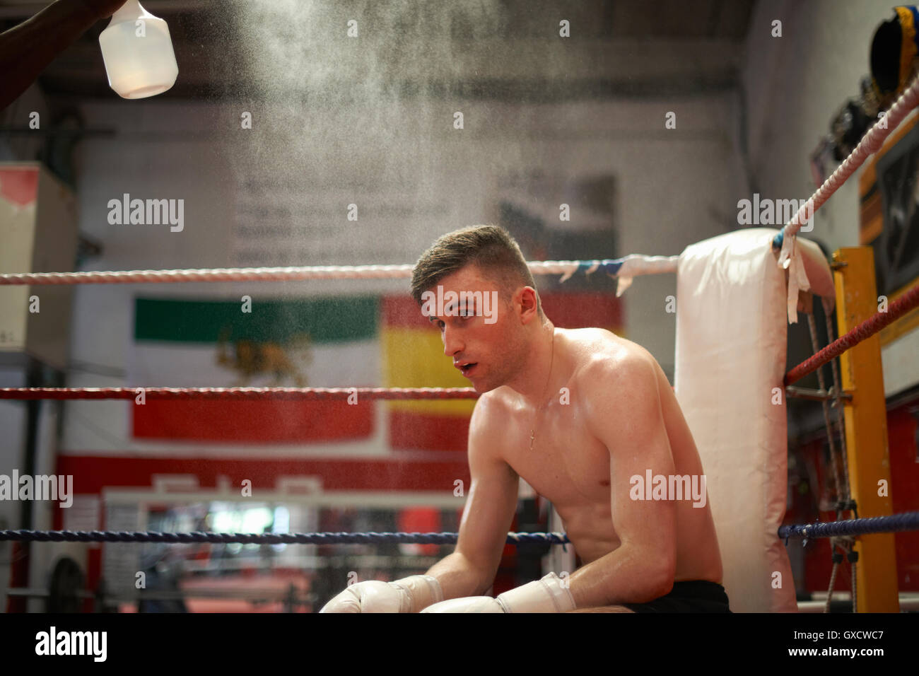 Boxer in seduta angolo del pugilato ring, esausto Foto Stock