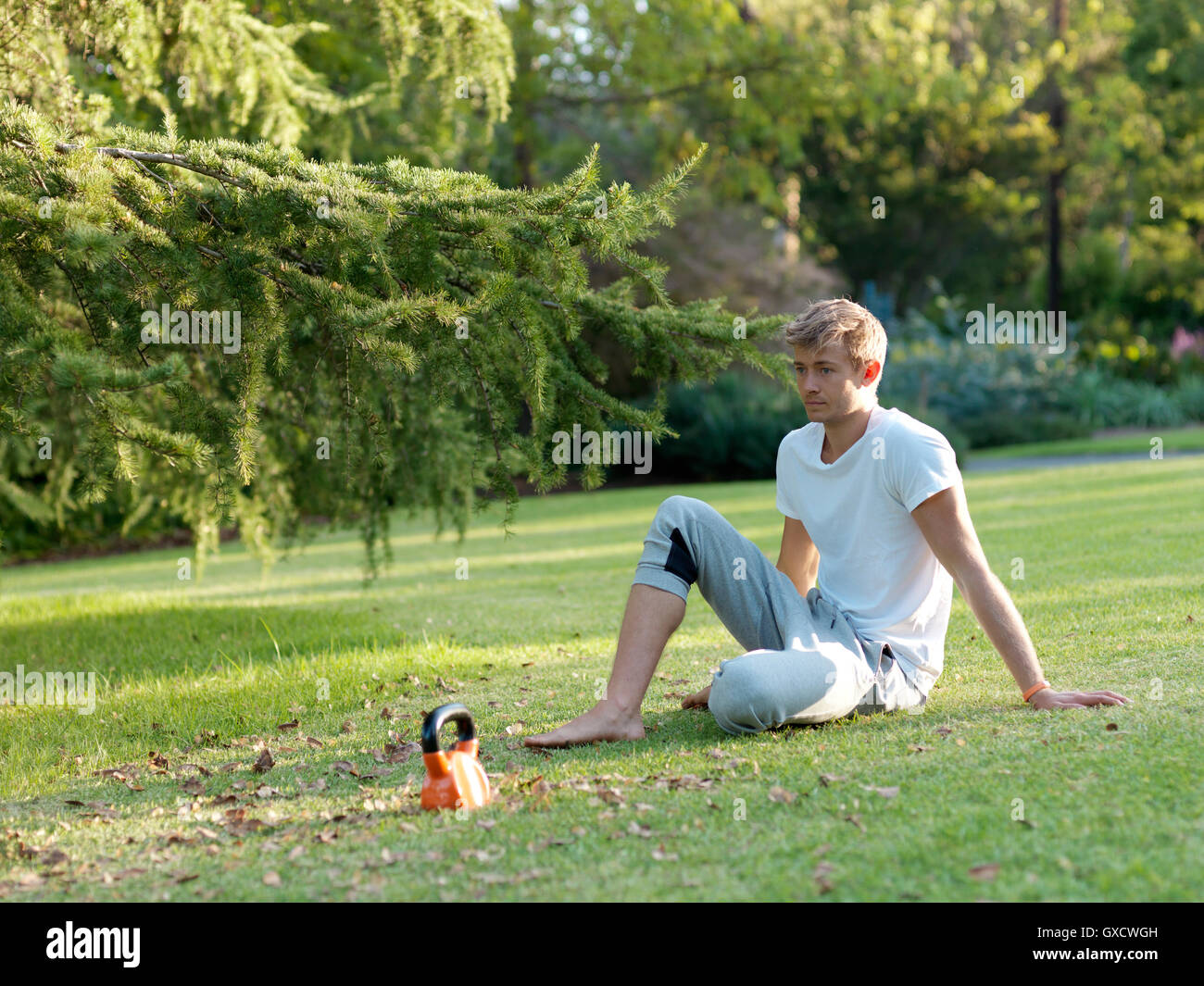 Giovane uomo relax su erba, prendendo una pausa dall'esercizio Foto Stock