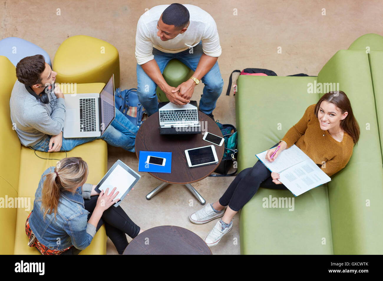 Vista aerea di quattro studenti maschi e femmine il brainstorming nell istruzione superiore college studio di spazio Foto Stock